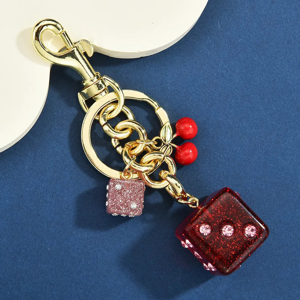 Square cherry two-tone dice keychain pendant on a metal ring.