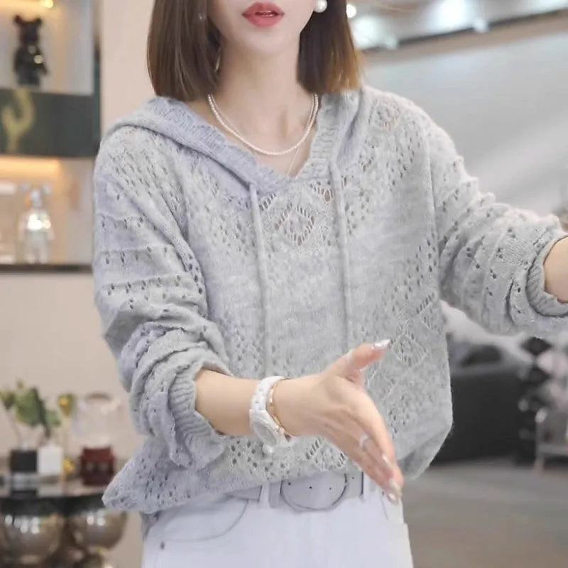Woman wearing a light blue, hooded crochet longsuit undershirt with a hollow knit pattern and long sleeves.