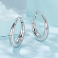 A pair of copper ring-shaped ear clip earrings with silver posts on a white background.