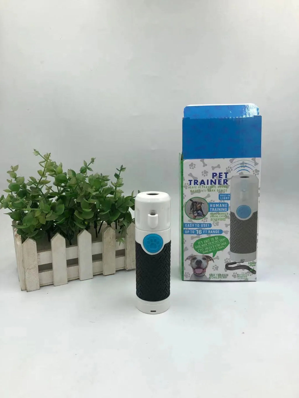 White handheld ultrasonic dog bark control trainer on a plain background