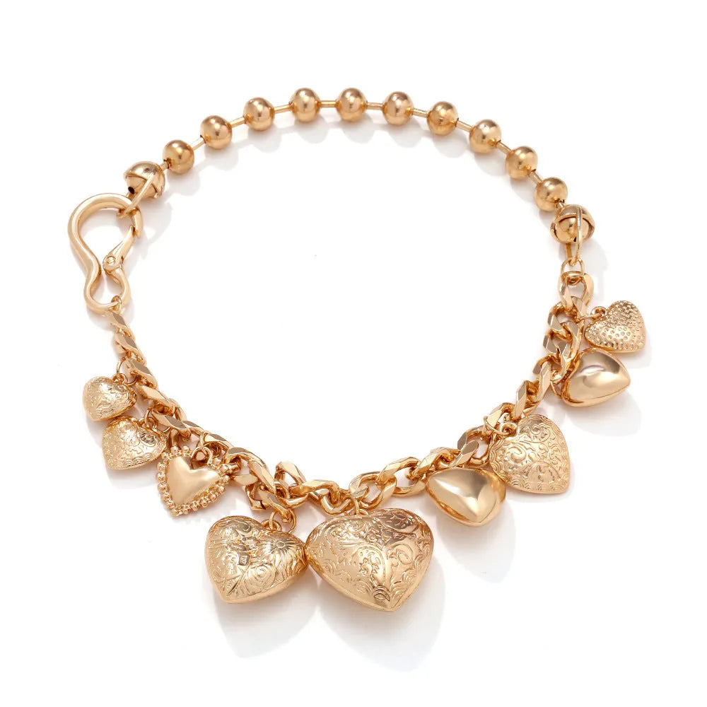 Carved heart-shaped alloy pendant on a metal chain necklace in gold colour.