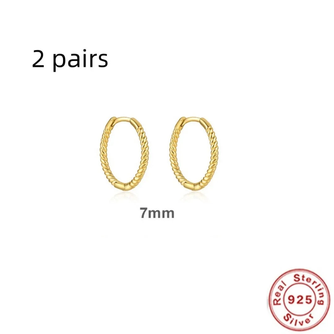 A pair of twisted sterling silver round earrings in a geometric design on a white background.
