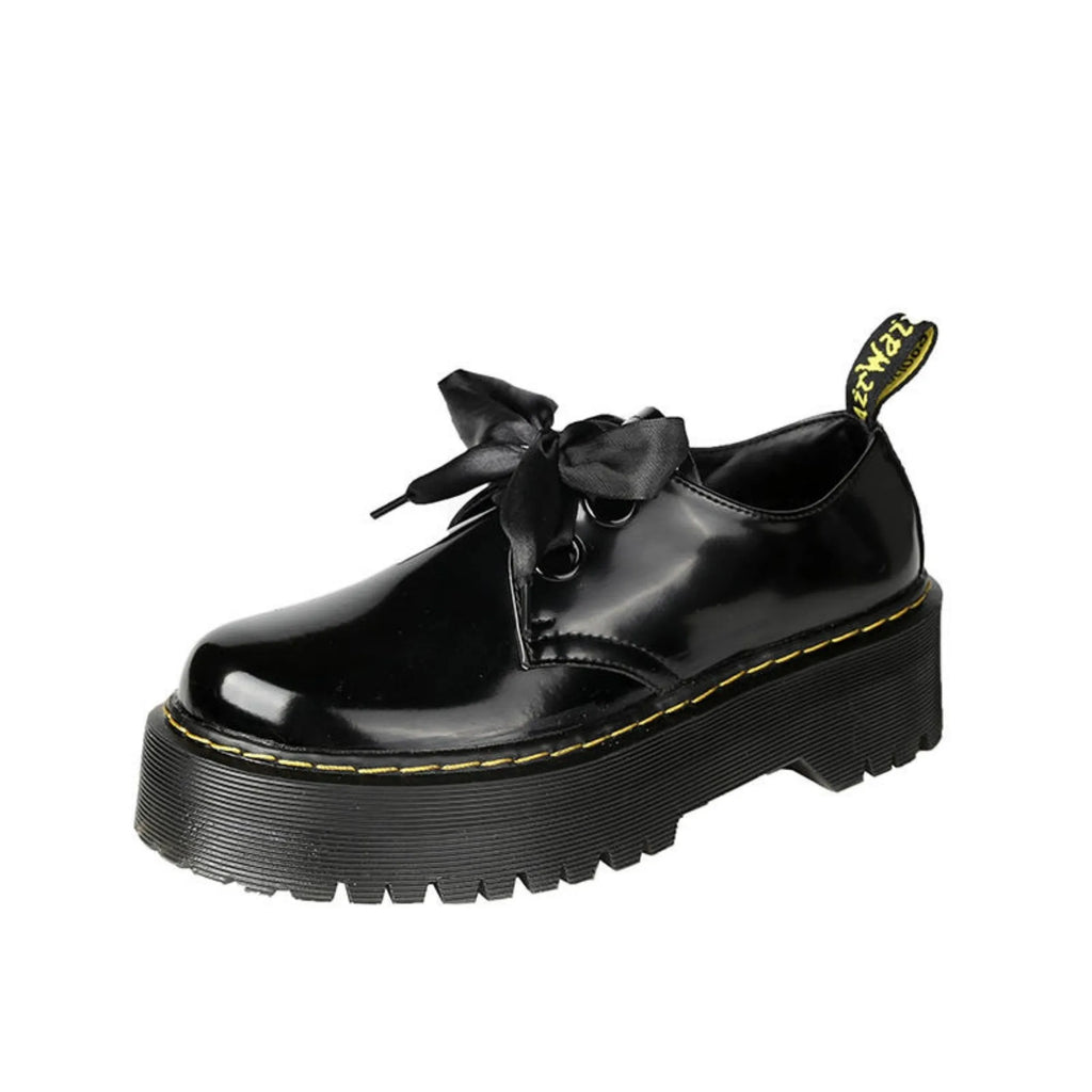 Black thick-soled women's lace-up shoes with ribbon and cross strap detailing on a white background