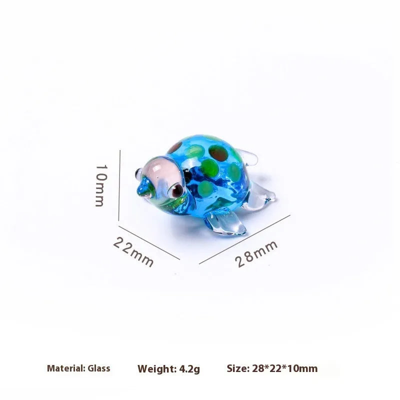 Geometric glass turtle ornament in a modern style with a coloured shell, displayed on a desktop.
