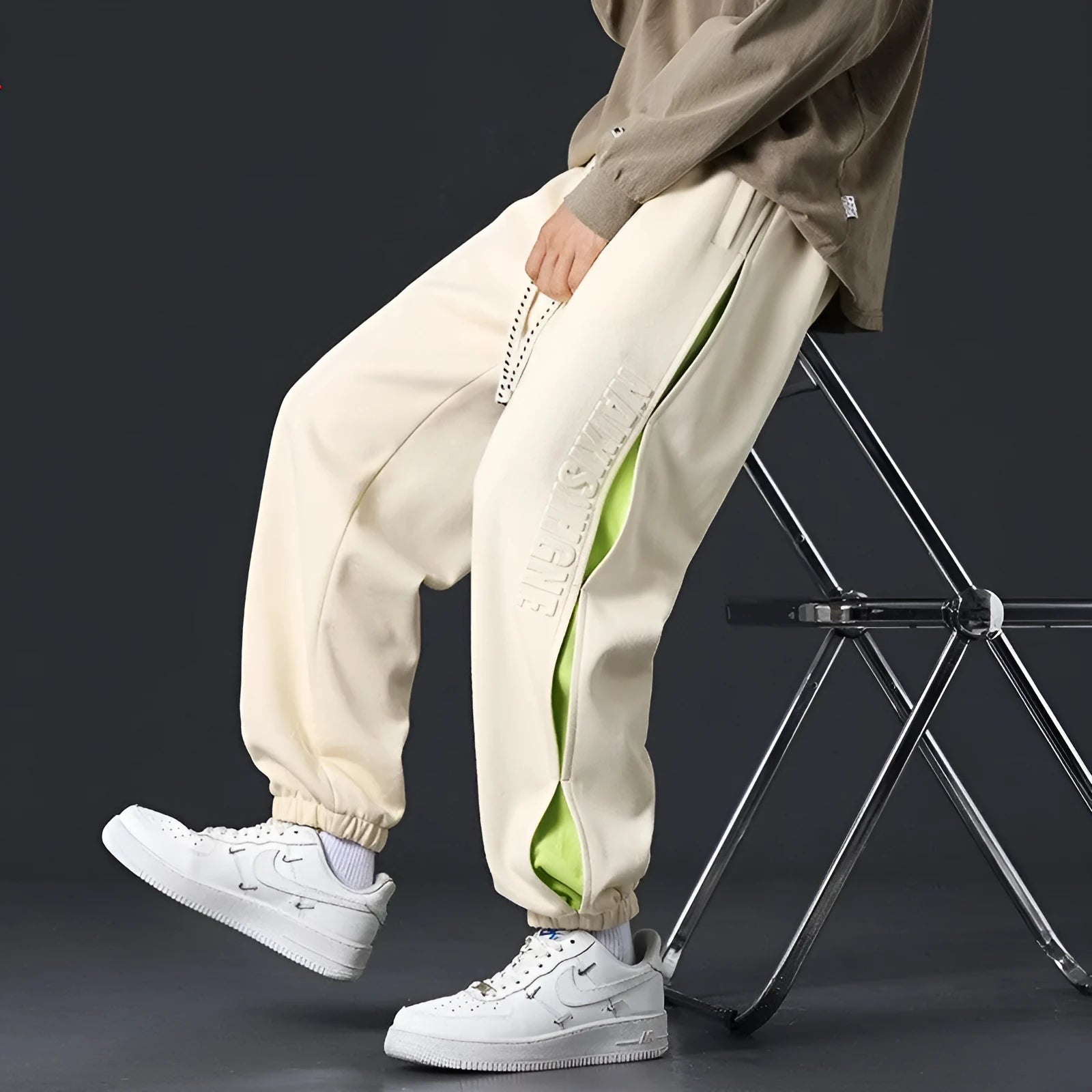 Man wearing loose grey-green cotton trousers with banded ankles and stitching detail.
