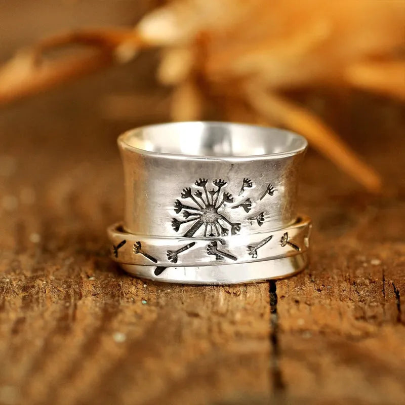 Silver electroplated alloy flower ring with rotating element on a hand.