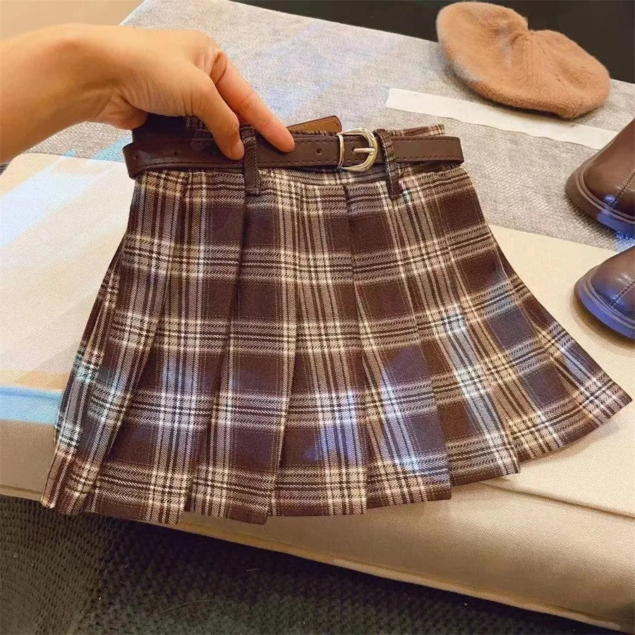 A girls' plaid pleated skirt in an A-line style, shown in a casual setting.