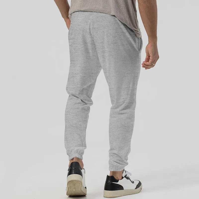 Men's loose tapered casual sweatpants in a grey cotton blend fabric with an elastic waistband.