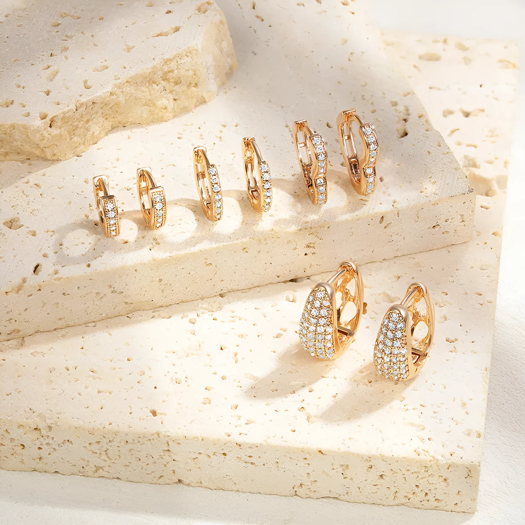 Gold plated brass heart-shaped ear clip earrings with zircon detail on a white background.