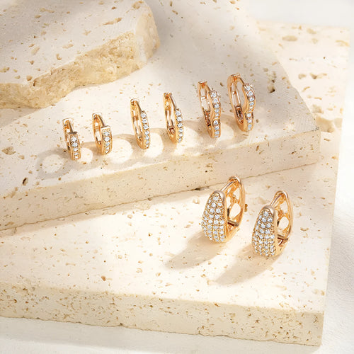 Gold plated brass heart-shaped ear clip earrings with zircon detail on a white background.