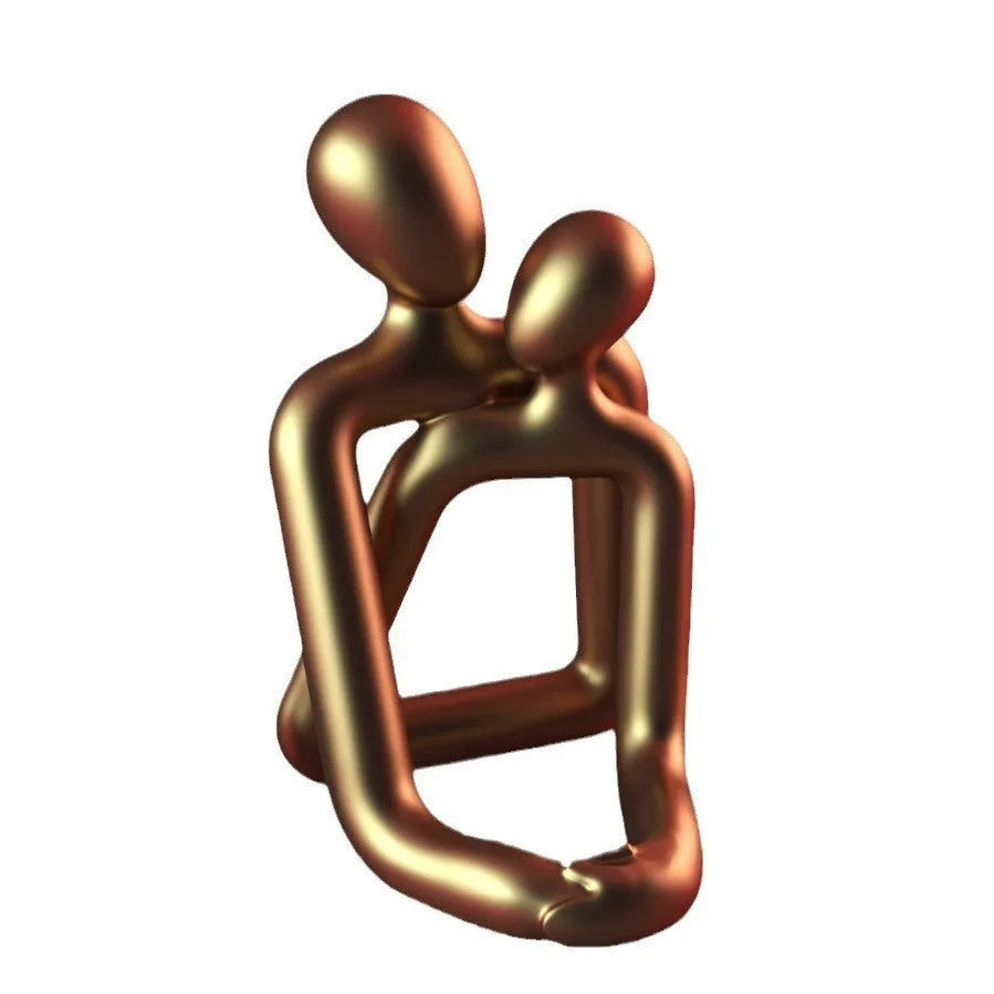 Modern loving couple resin statue in gold or milky white on a wooden shelf.